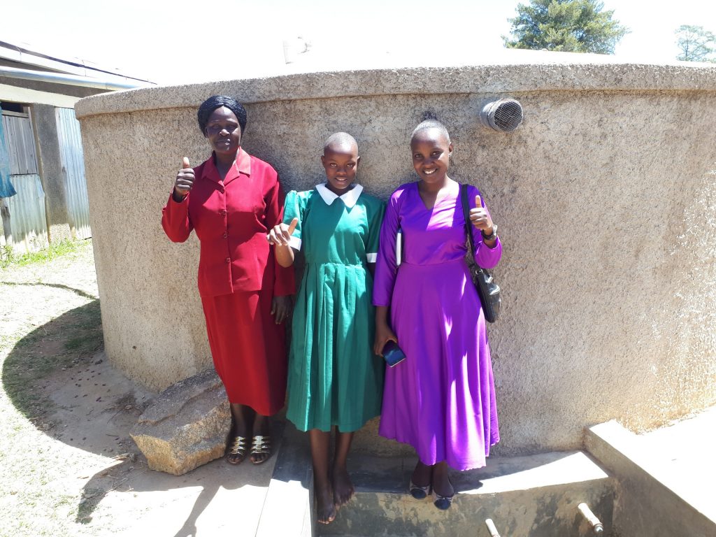 The Water Project : kenya4657-field-staff-joan-were-with-alice-and-jackyline-at-the-tank