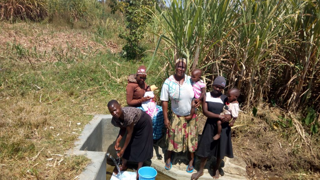 The Water Project : kenya4846-women-from-the-community-lined-up-to-fetch-water-from-the-spring