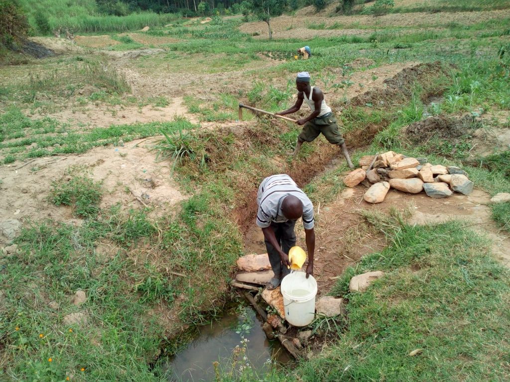 The Water Project : 5-kenya19123-fetching-water-as-the-man-behind-clears-drainage-channel-as-advised