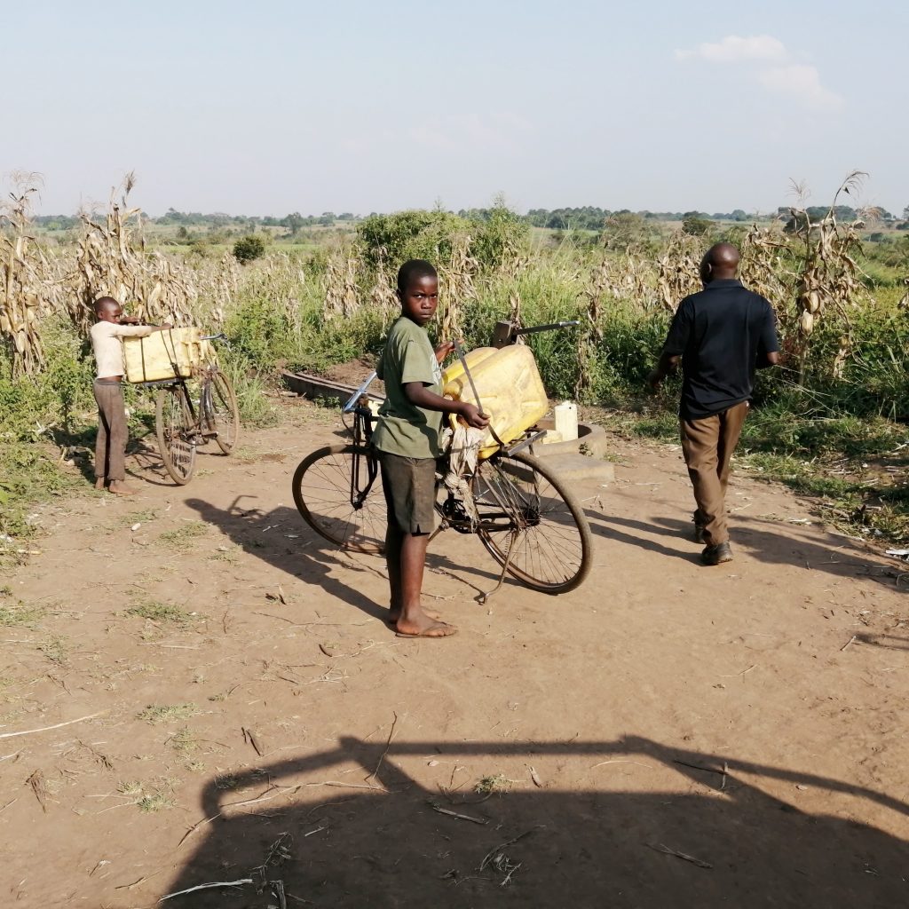 The Water Project : uganda21604-tying-down-water-jugs-onto-bikes