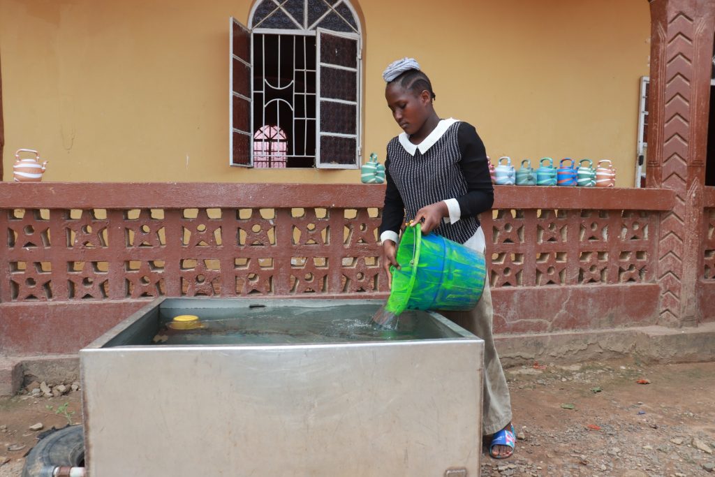 The Water Project : sierraleone21546-pouring-water-inside-storage-container-at-mosque-3
