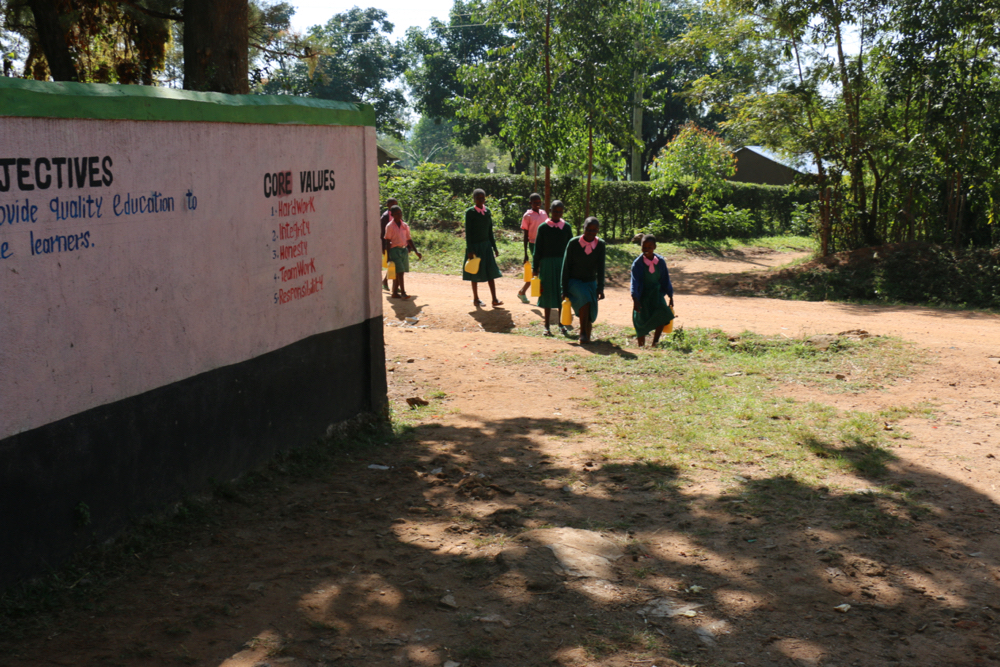 The Water Project : kenya21352-students-arrive-carrying-water-from-home-1-2