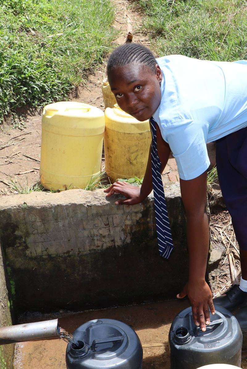 A student fills jerrycans at the crowded spring below St. Gerald Shitaho Polytechnic.
